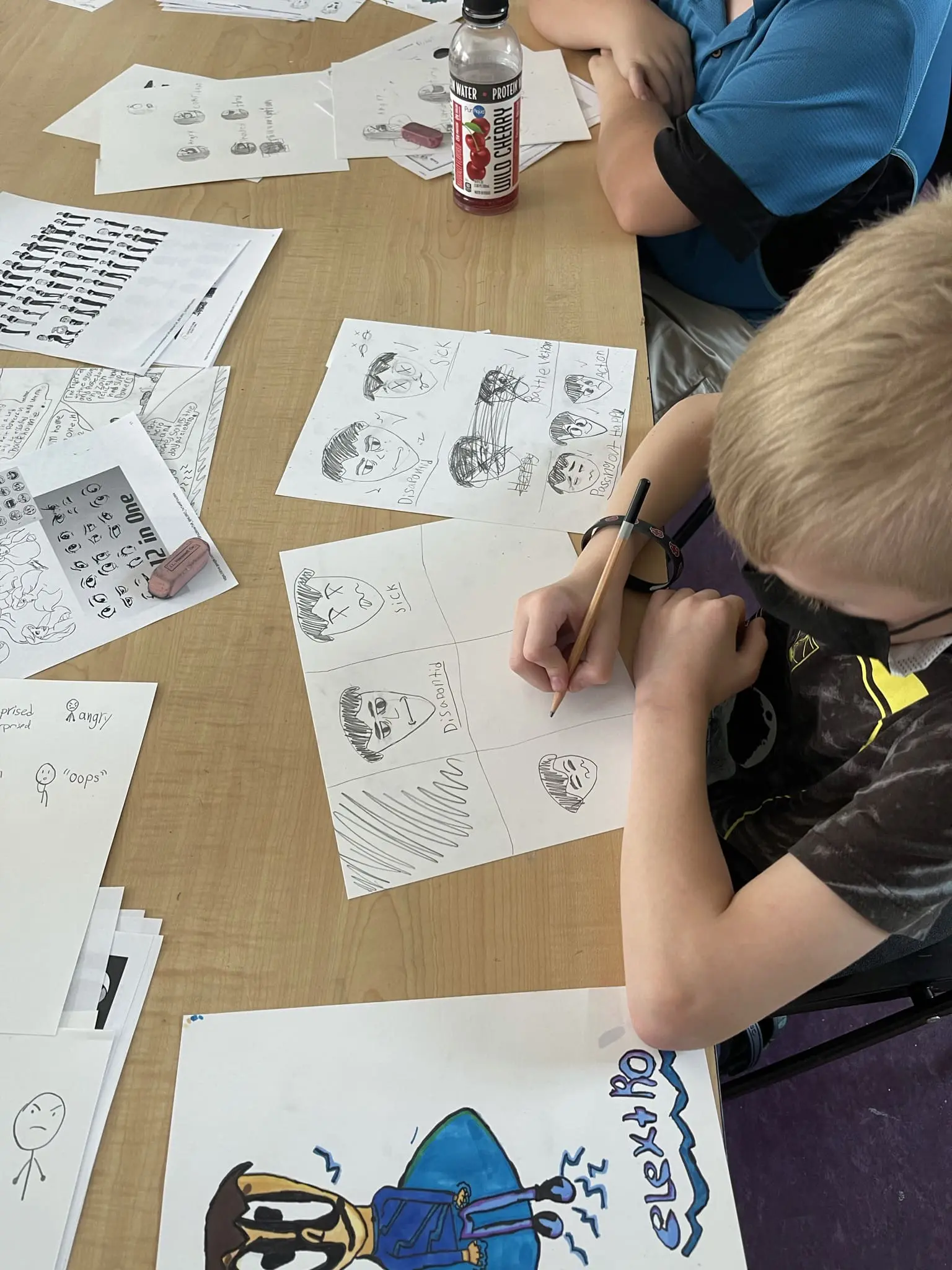 boy is holding a pencil and drawing a blue superhero
