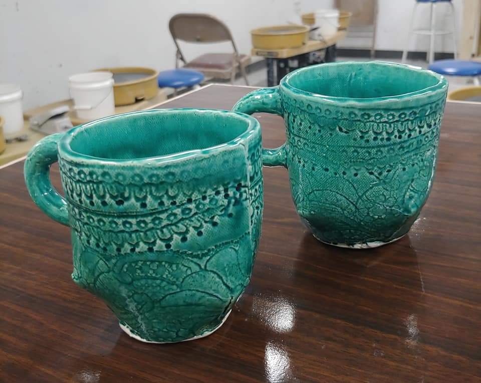 two teal ceramic mugs on a table